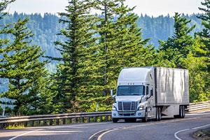 tractor trailer driving along tree-lined highway