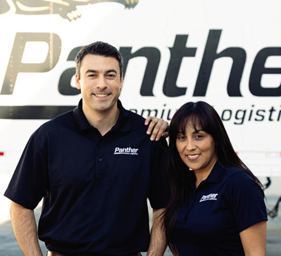 Same-household driving team standing in front of Panther truck.