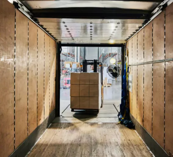 Forklift loading a pallet of boxes onto a truck.