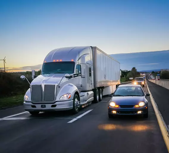 Cars driving alongside a semi truck on the highway.