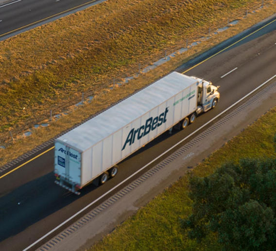 Semi truck pulling an ArcBest dedicated trailer down a highway 