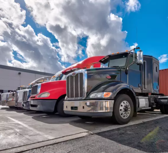 Semi trucks lined up outside a warehouse.