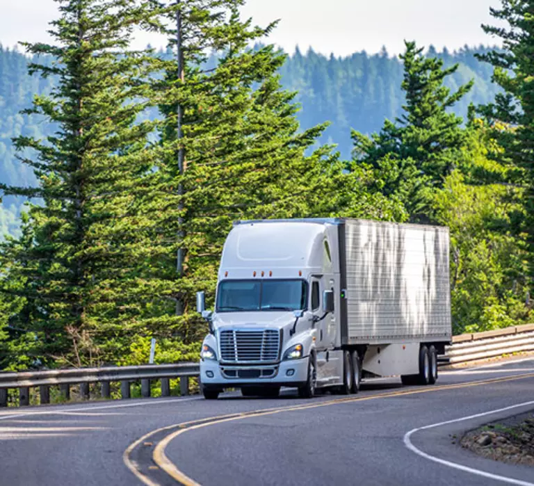 tractor trailer driving along tree-lined highway