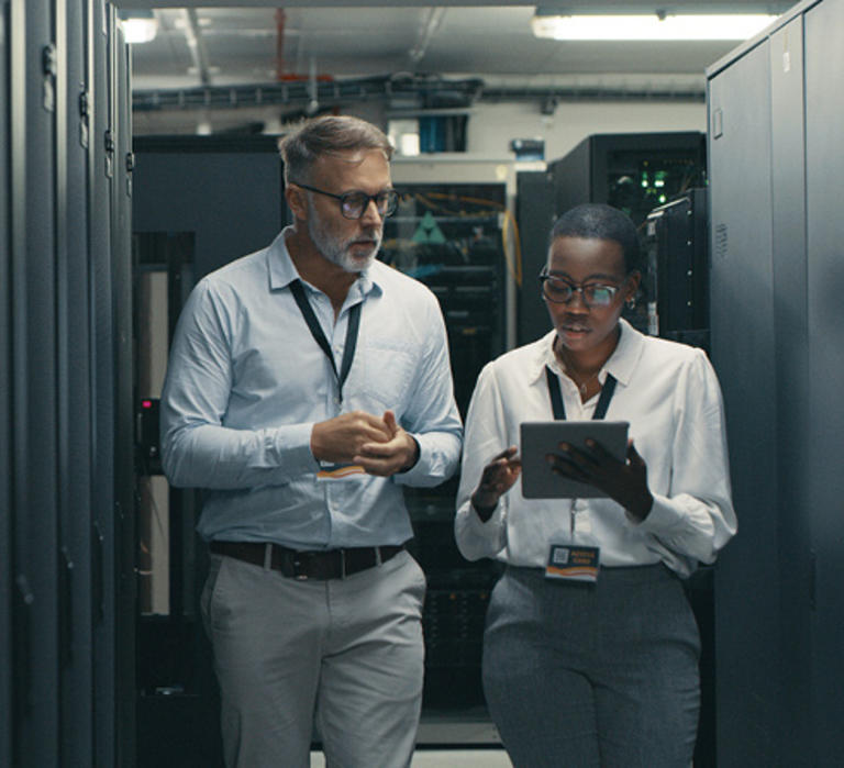 Man and woman walk through server room discussing information security.