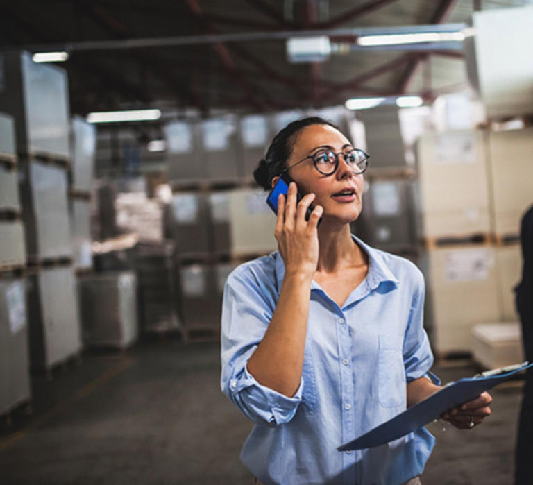 Woman standing in a warehouse on the phone with an expedite shipper