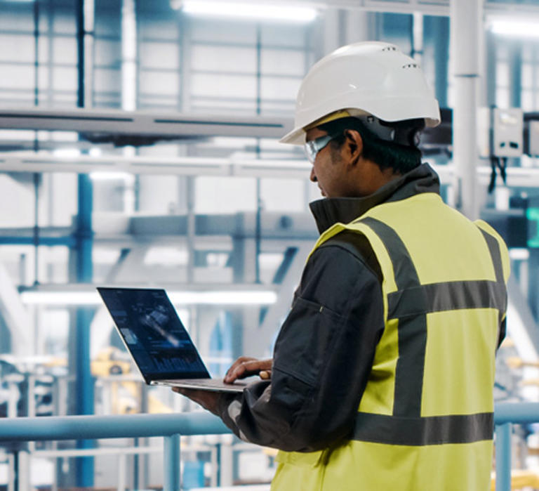 Person standing in warehouse with laptop planning logistics operations 