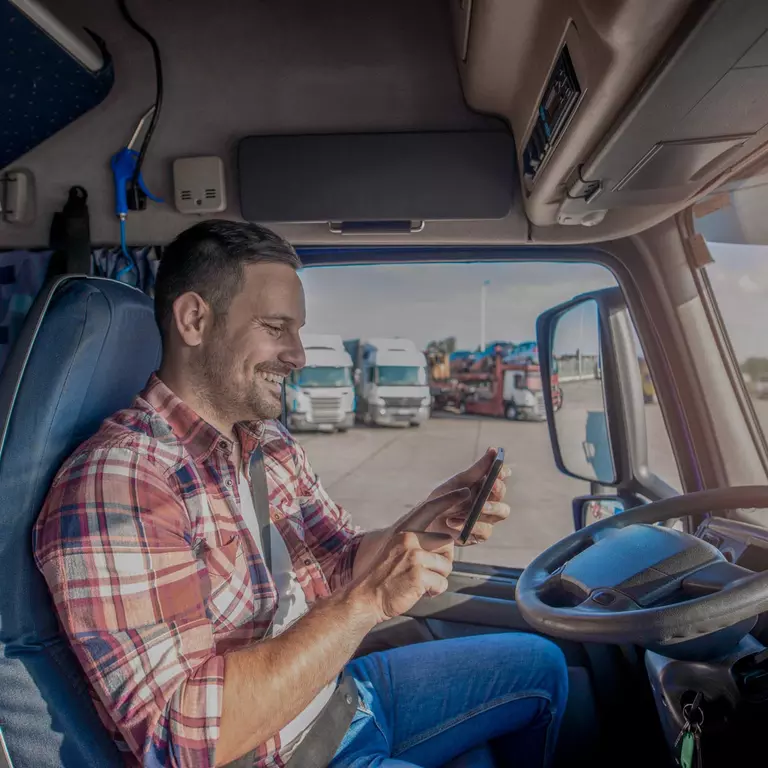 Truck driver looking up driver appreciation week promotions on his phone while parked.