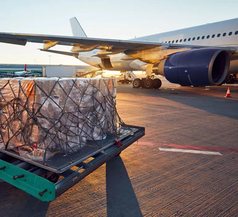 Air cargo getting ready to be loaded into a plane on a runway.