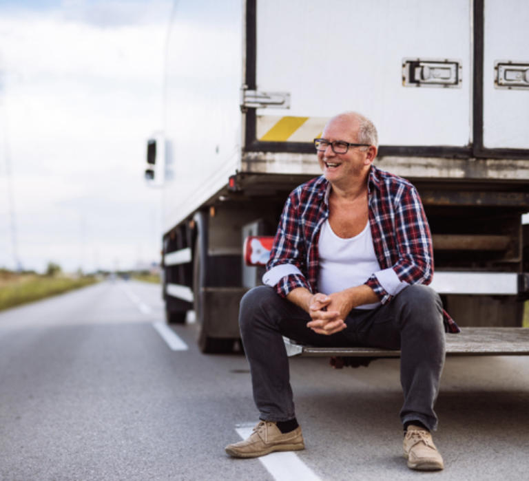 Smiling man sits on the liftgate of a truck.