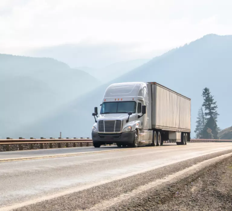 Truck driving down a highway moving a full truckload shipment.