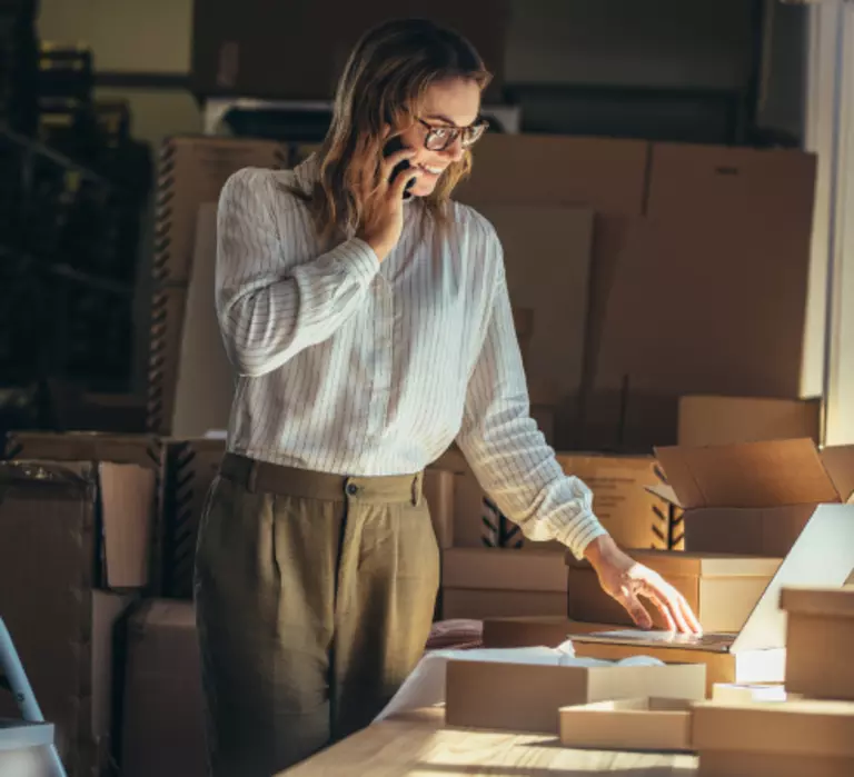 Woman talking on the phone while looking over paperwork for her small business.