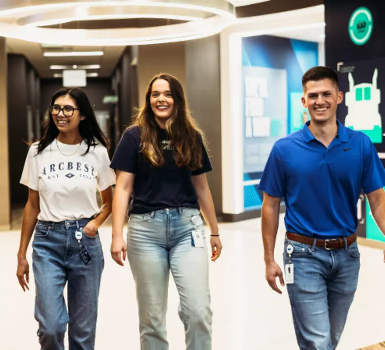 Three ArcBest employees walking down a hallway at the office.