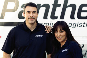 Same-household driving team standing in front of Panther truck.