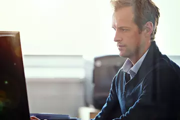 Man sitting at a computer in an office.