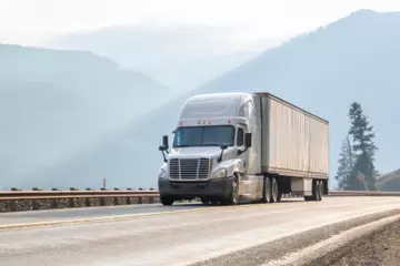 Truck driving down a highway moving a full truckload shipment.