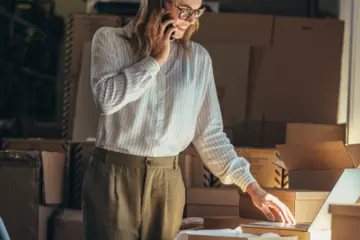 Woman talking on the phone while looking over paperwork for her small business.