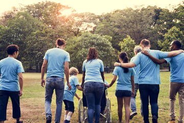 Volunteers walking away from camera with their arms around each other.