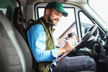 Truck driver sitting in cab of truck.