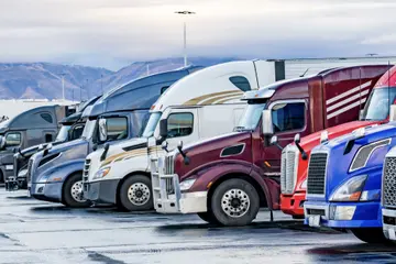 Semi Trucks lined up in a parking lot. 