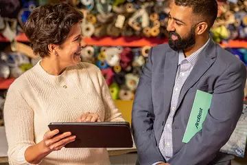Man and woman discussing small business shipment data on a tablet.