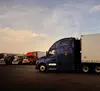 Blue semi truck parked next to other trucks.