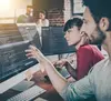 A man and woman look over code at a computer.