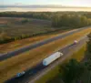 Aerial view of a highway with cars and a truck driving down it.